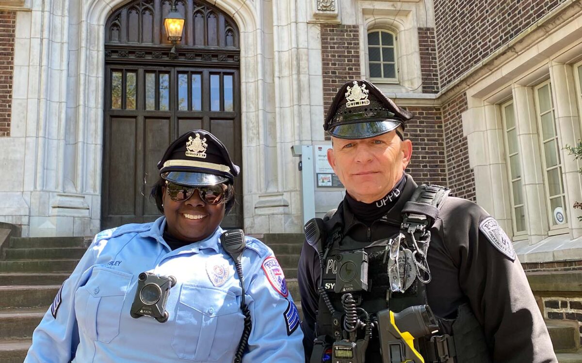 UPPD Officers in uniform smiling in front of brick building.
