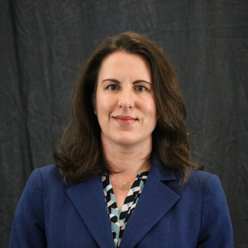 Photo of a woman with brown hair wearing a blue suit jacket